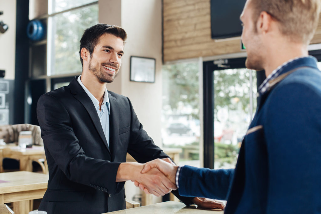 Two businessmen shaking hands in a cafe